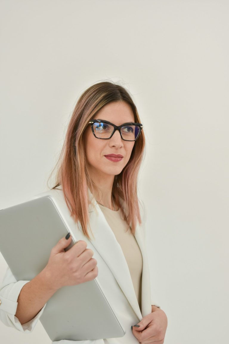 Bussines woman in a white jacket holdind a gray laptop.